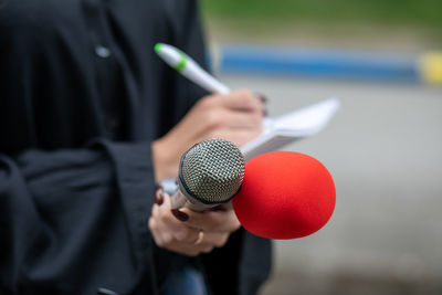 Close-up of man holding camera while standing outdoors