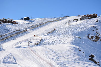 Snow covered landscape against clear blue sky