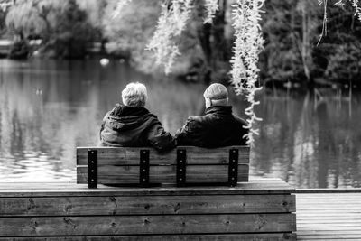 Rear view of woman sitting on bench in lake