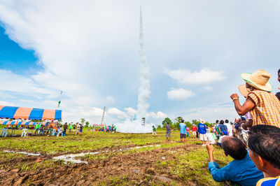 People watching rocket launch on field