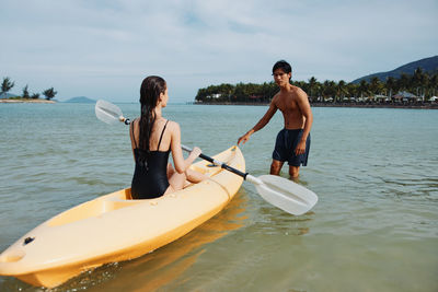 Man kayaking in sea against sky