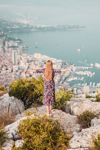 Rear view of woman standing by sea against sky