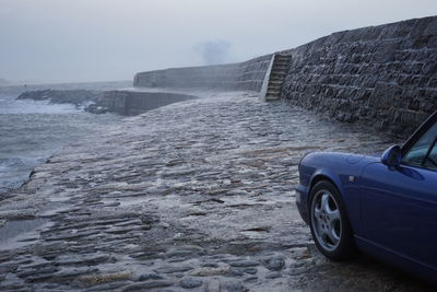 Scenic view of parked car in front of stormy beach