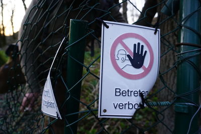 Close-up of warning sign on metal fence