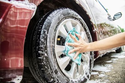 Cropped hands of man washing car tire