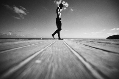 Low section of woman standing on snow against sky