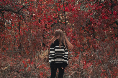 Rear view of woman standing in forest during autumn