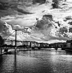 Bridge over river against cloudy sky