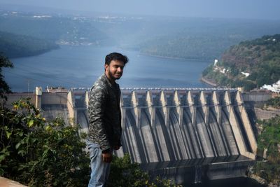 Portrait of smiling man standing on mountain against dam