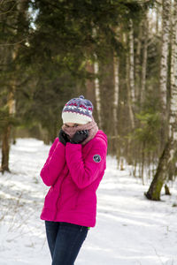 Woman with pink umbrella standing in park during winter