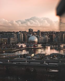 Cityscape by river against sky at dusk