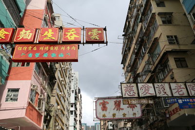 Low angle view of information sign hanging against buildings in city