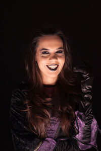 Portrait of smiling young woman against black background