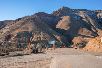 Empty asphalt curvy road through mountains in sunny summer day