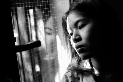 Close-up of thoughtful woman looking through window