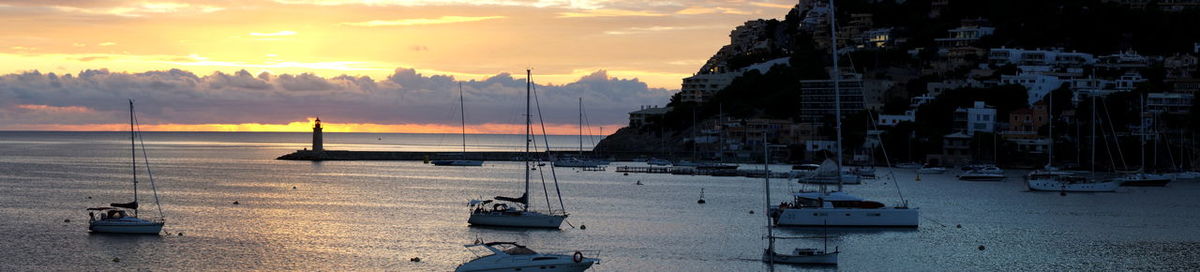 Boats moored on sea against sky during sunset