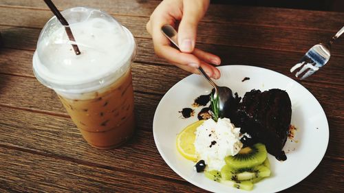 Close-up image of person having cake and drink on table