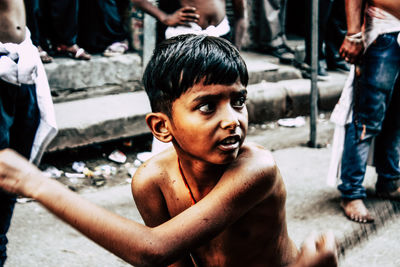 Portrait of shirtless boy on street in city