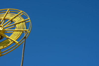 Low angle view of ferris wheel against blue sky