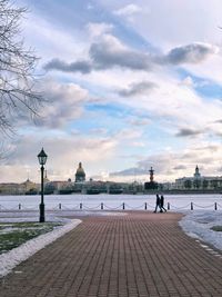 Friends walking by river in city against sky