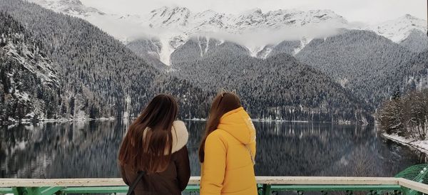 Rear view of women on lake against mountains during winter