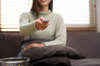 Young woman using mobile phone while sitting on sofa at home