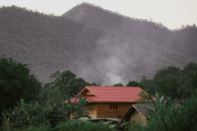 House by trees and mountains against sky