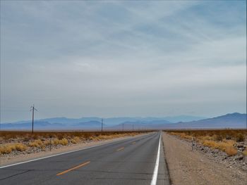 Road passing through landscape against cloudy sky