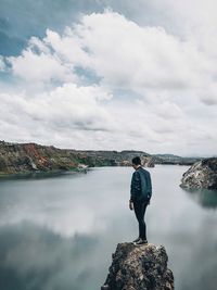 Woman standing on riverbank against sky