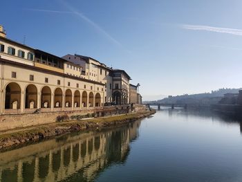 Reflection of buildings in river against clear blue sky