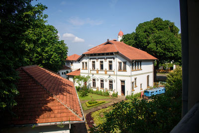 Houses by trees and buildings against sky