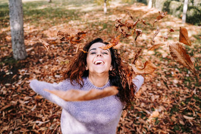 Portrait of a smiling young woman in autumn leaves