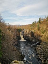 Scenic view of river against cloudy sky