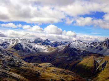 Scenic view of snow covered mountains against cloudy sky