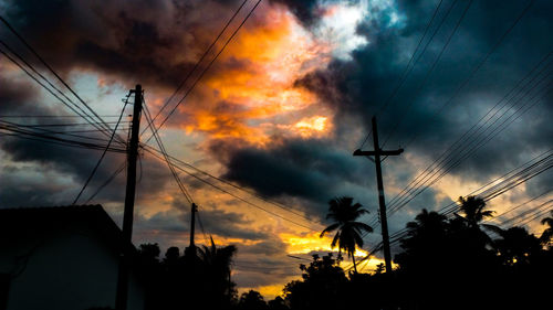 Low angle view of electricity pylon against cloudy sky