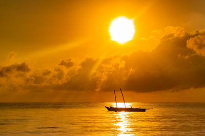 Silhouette sailboat in sea against sky during sunset