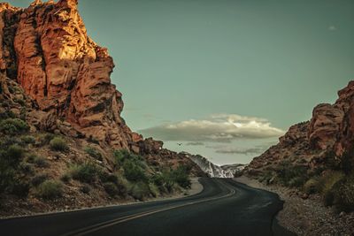 Road amidst rock formation against sky