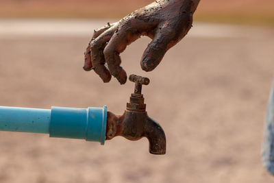 Close-up of dirty hand touching faucet outdoors