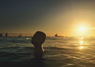 Silhouette woman in sea during sunset