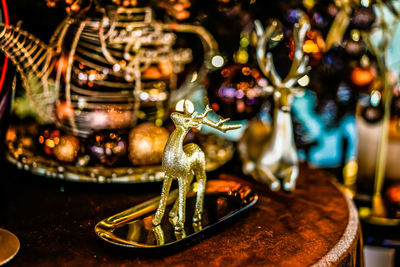 Golden glitter deer sculpture decorate on the wooden table on blurred background. 
