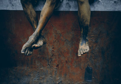 Low section of men with dirty legs against rusty wall