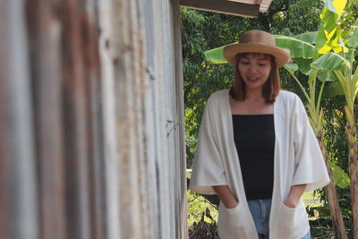 Woman wearing hat standing by metallic wall