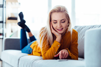 Young woman using phone while sitting on sofa