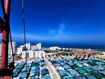 High angle view of buildings by sea against blue sky