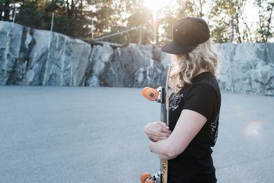 Skater girl holding her board looking at the sunset at skate park