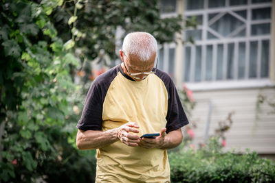 Side view of man using mobile phone while standing outdoors