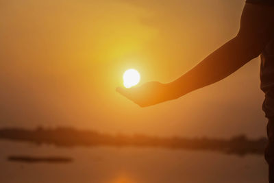 Silhouette hand against bright sun during sunset