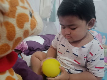 Cute boy holding toy while relaxing on bed at home