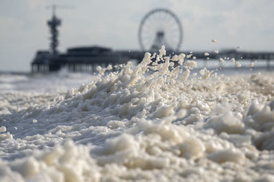 Foam covered land by sea against sky