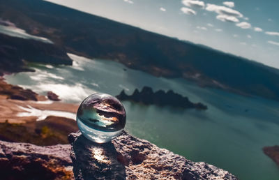 Close-up of crystal ball on rock against sea